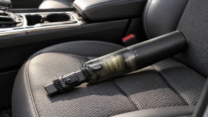 Baseus handheld car vacuum resting on a charcoal car seat